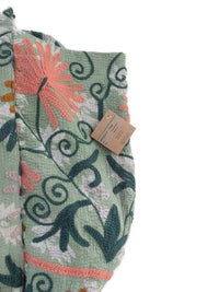 Detail of Suzani embroidery in light green, dark green, pink and ochre on a vintage beach bag