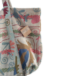 Detail of Suzani embroidery in pink, blue, green and sand on a vintage beach bag